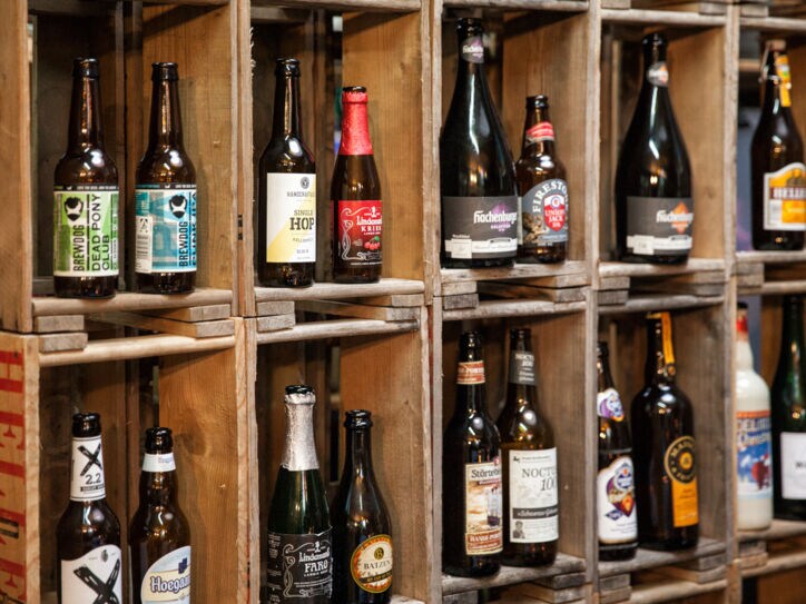 In einem Holzregal stehen verschiedene Bierflaschen