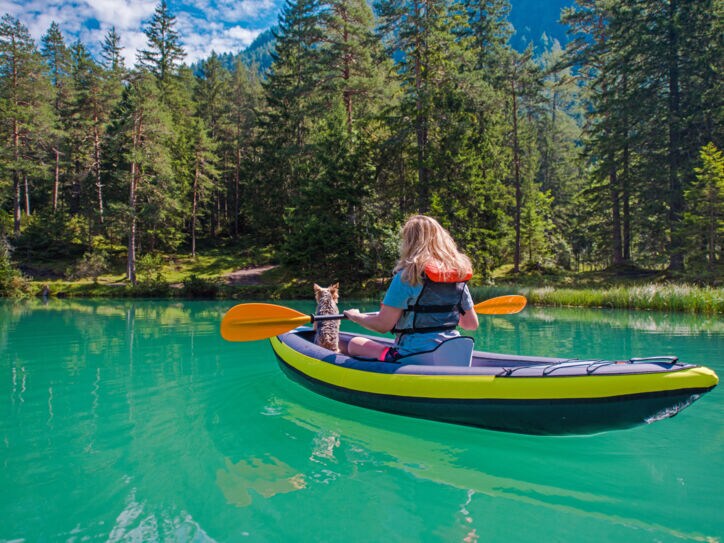 Eine Frau mit einem Hund im Kanu auf einem türkisfarbenen Fluss