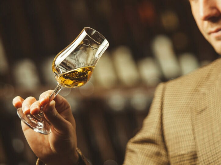 Ein Mann schwenkt ein Whisky Nosing Glas in seiner Hand