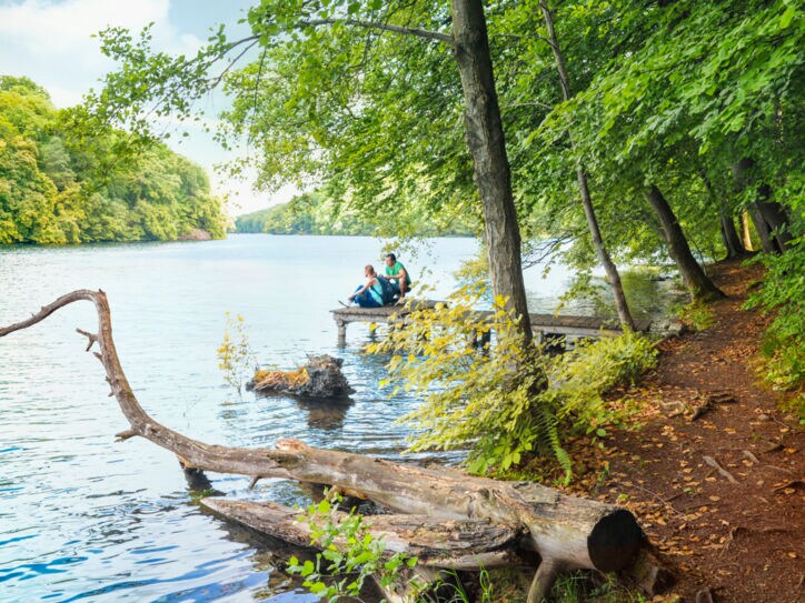 Wanderer pausieren auf einem Steg am Schmalen Luzin im Naturpark Feldberger Seenlandschaft