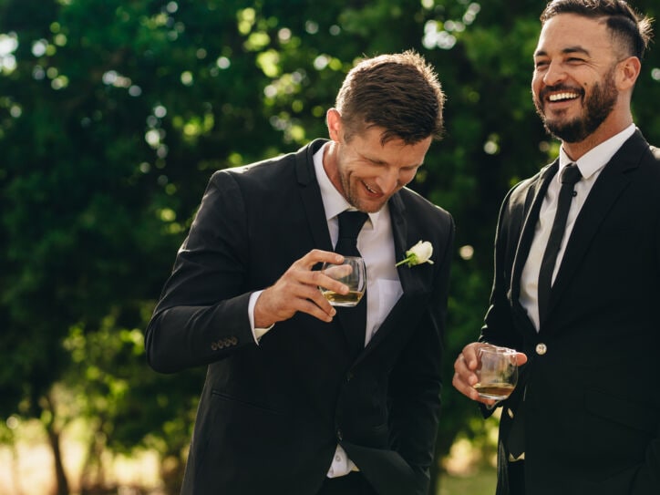 Bräutigam und Trauzeuge trinken und lächeln während der Hochzeitsfeier