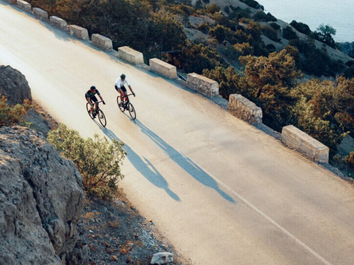 Zwei professionelle Radfahrer fahren mit ihren Rennrädern eine Küstenstraße entlang