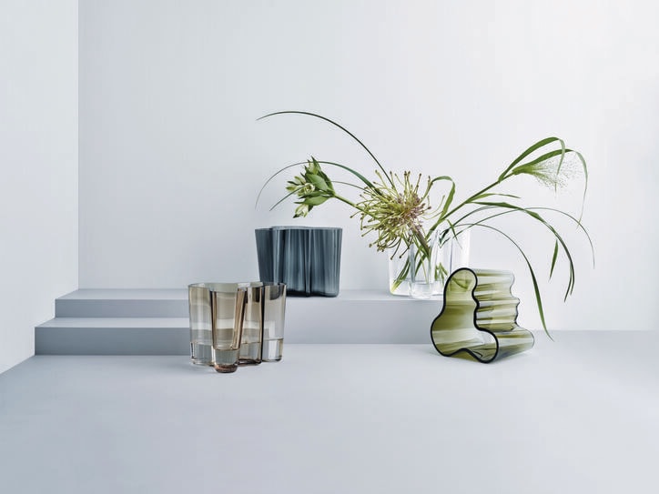 Mehrere Designervasen stehen in einem grauen Raum.