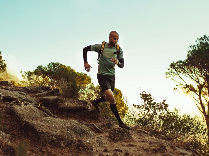 Ein Mann rennt mit Rucksack auf dem Rücken durch unbefestigtes Gelände