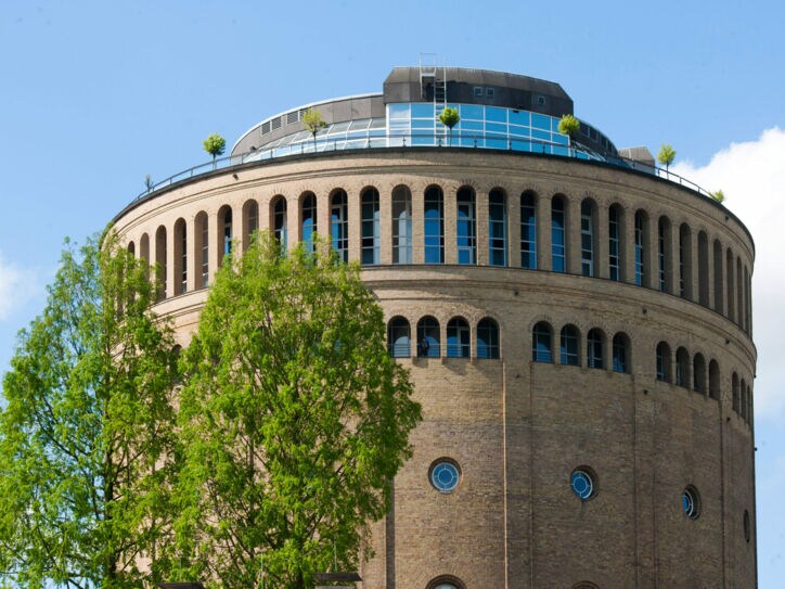 Ein runder, historischer Wasserturm mit moderner Terrasse