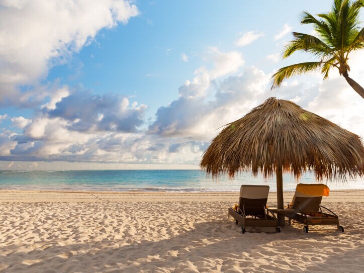 Zwei Liegen unter einem Sonnenschirm am Strand