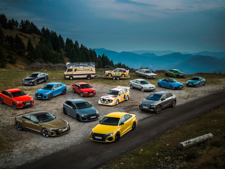 Mehrere Autos stehen vor einer Bergkulisse