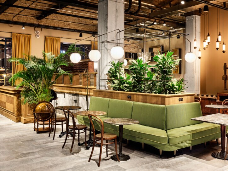 Geräumige Lobby des Berliner Hotels im Telepgraphenamt mit grünem Loungebereich und braunen Designstühlen