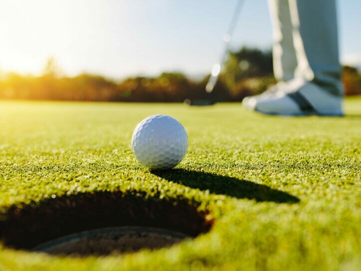 Nahaufnahme eines Golfballs vor dem Loch auf einem Putting-Green