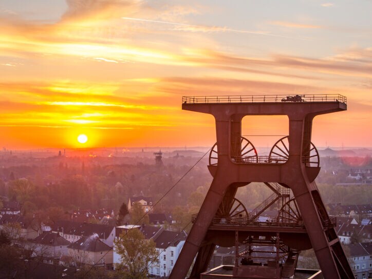 Blick auf Doppelbock-Fördergerüst vom Dach der Kohlenwäsche des UNESCO-Welterbes Zollverein beim Sonnenaufgang