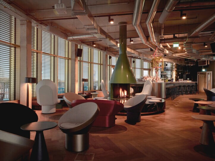 Moderne Bar mit Sitzgruppen um einen Kamin und einer geschwungenen Fensterfassade mit Panoramablick