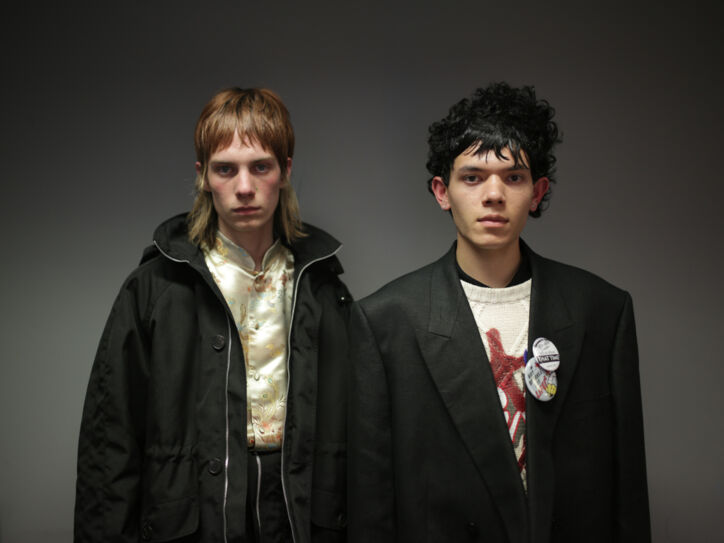 Zwei männliche Models posieren mit schwarzen Jacken und rockigen Stufenhaarschnitten