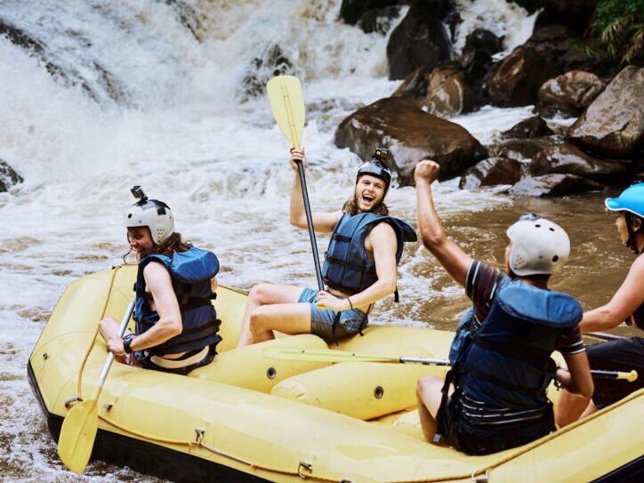 Aufnahme einer Gruppe fröhlicher Personen in einem Schlauchboot, die einen wilden Fluss hinabfahren