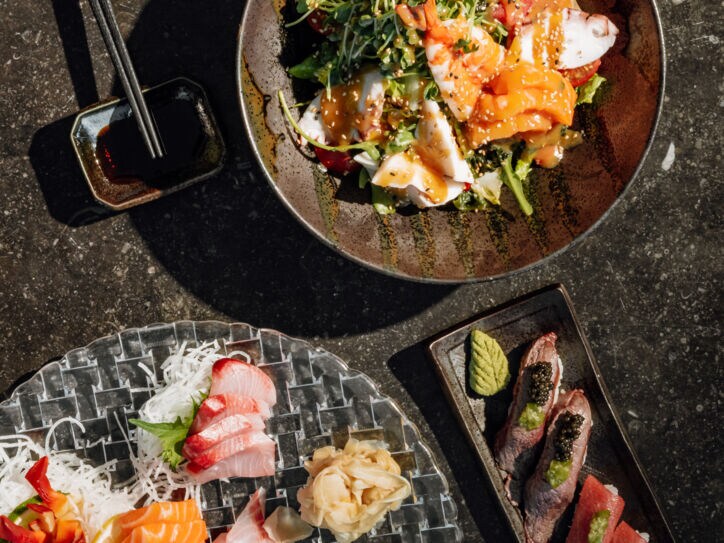 Aufsicht mehrerer Teller mit Sushi und anderer asiatischen Speisen.