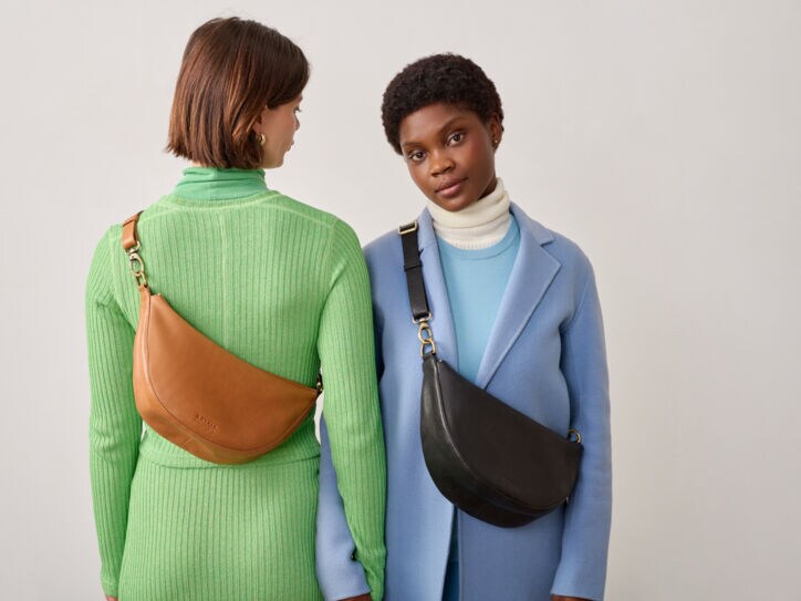 Zwei weibliche Models mit halbmondförmigen Umhängetaschen aus Leder.