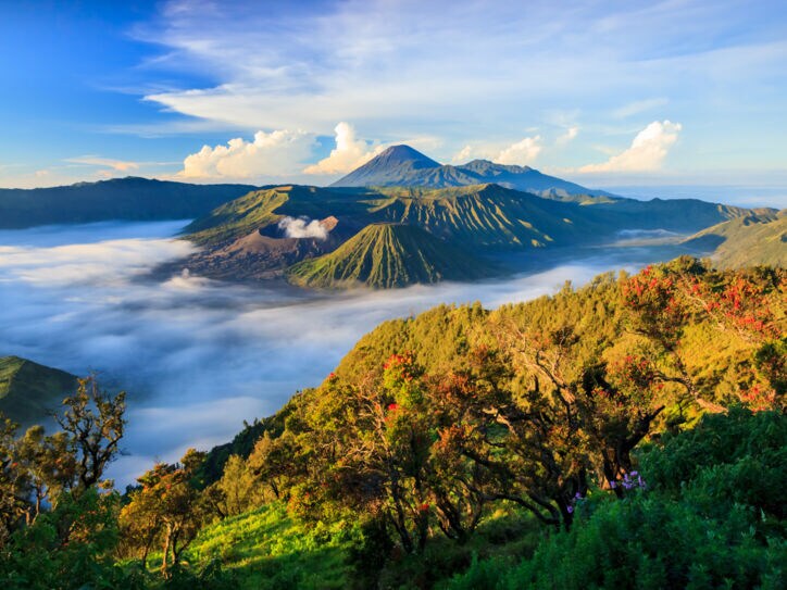 Landschaftsaufnahme über die indonesische Insel Java mit Vulkanen im Hintergrund.