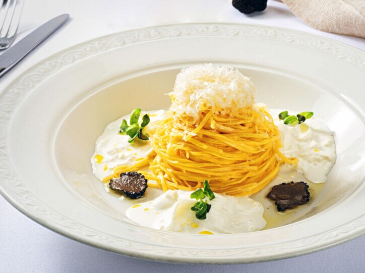 Spaghetti-Gericht mit Burrata und Trüffel, edel angerichtet auf einem weißen Teller.