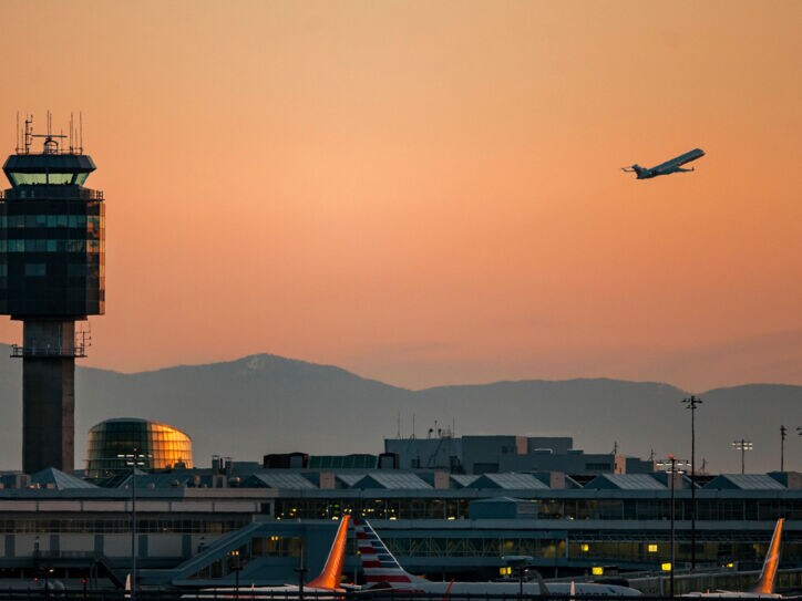 Tower des Vancouver Airports bei Sonnenuntergang und ein startendes Flugzeug.