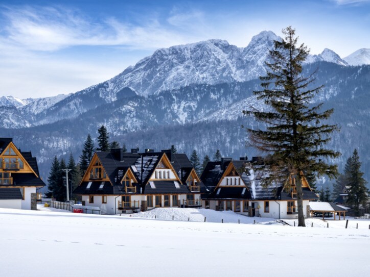 Das Dorf Kościelisko in der polnischen Tatra, im Hintergrund schneebedeckte Berge.