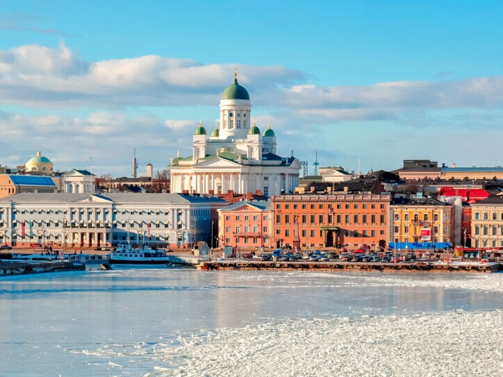Stadtpanorama von Helsinki mit Dom an einer zugefrorenen Wasserfläche im Vordergrund.
