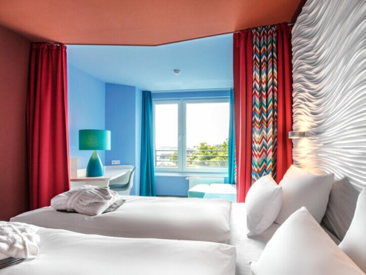 Modernes Hotelzimmer mit farbenfrohen Wänden und Strandblick.