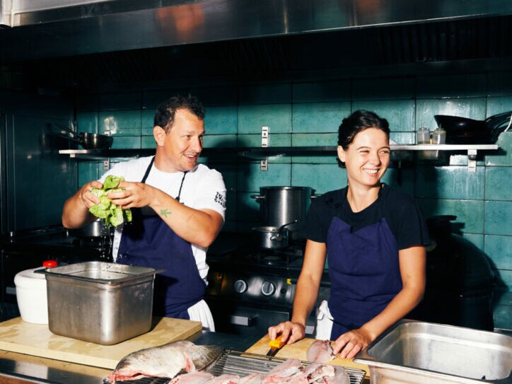 Koch und Köchin bereiten Salat und Fisch in der Restaurantküche vor.