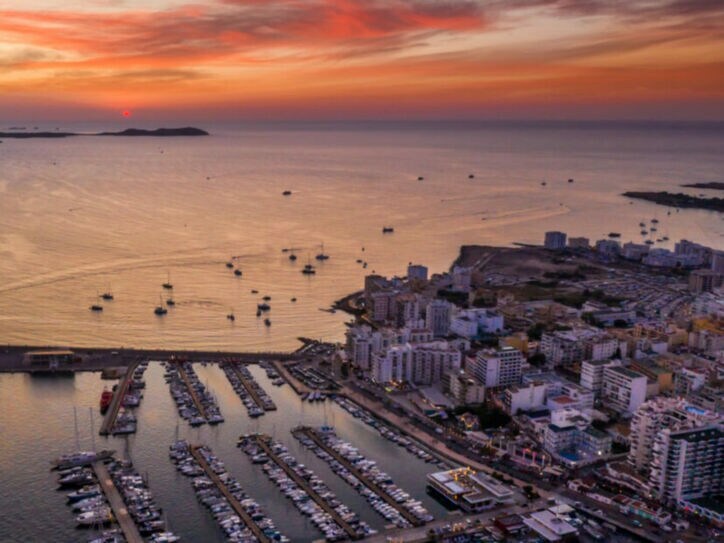 Luftaufnahme eines Hafens mit vielen Booten und Yachten bei Sonnenuntergang mit orangefarbenem Himmel