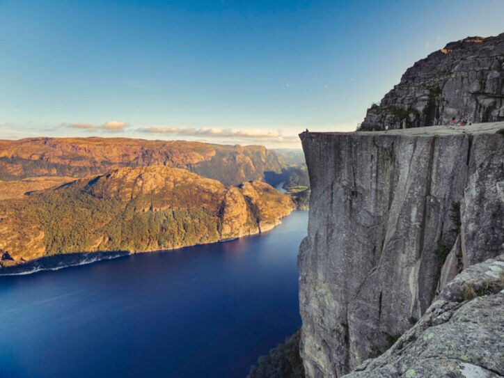 Fjordlandschaft an einem klaren Tag mit Personen auf einer beeindruckenden Felsklippe.