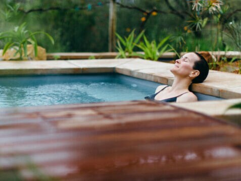 Eine Frau liegt entspannt in einem Whirlpool in der Natur
