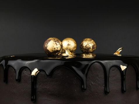 Schokoladentorte, verziert mit drei Kugeln, die mit Blattgold ummantelt sind