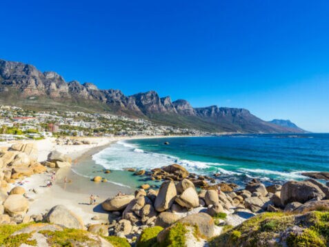 Felsige Strandbucht bei Kapstadt mit Gebirgskette im Hintergrund