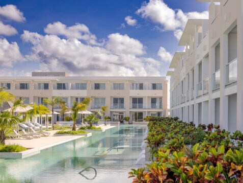 Moderne, dreistöckige Hotelanlage mit begrünter Poollandschaft.