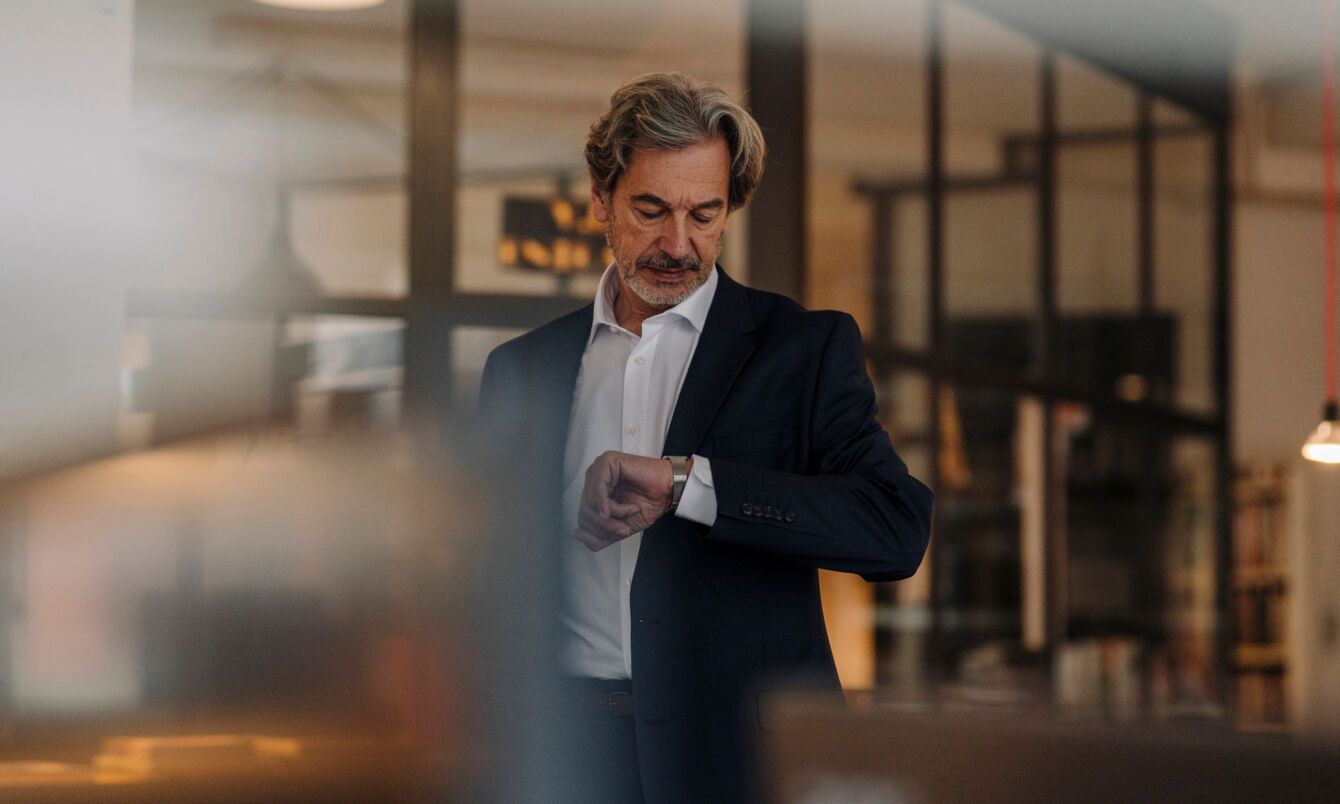 Ein Mann in Anzug schaut auf seine Armbanduhr