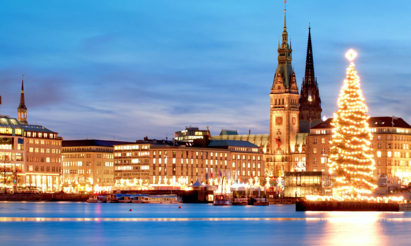 Erleuchtetes Panorama von Hamburg mit Rathaus und Weihnachtsbaum an der Alster