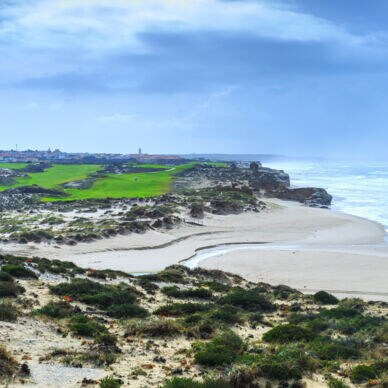 Ein hügeliger Golfplatz neben einem Sandstrand an einem wilden Küstenabschnitt