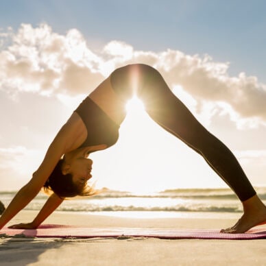 Eine Frau in einer Yoga-Pose am Strand. 