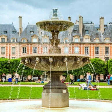Brunnen mit fließendem Wasser im Place des Vosges, Paris, vor historischen Gebäuden und Bäumen