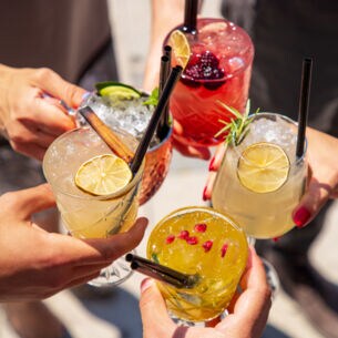 Fünf Hände halten Gläser mit fruchtigen Drinks