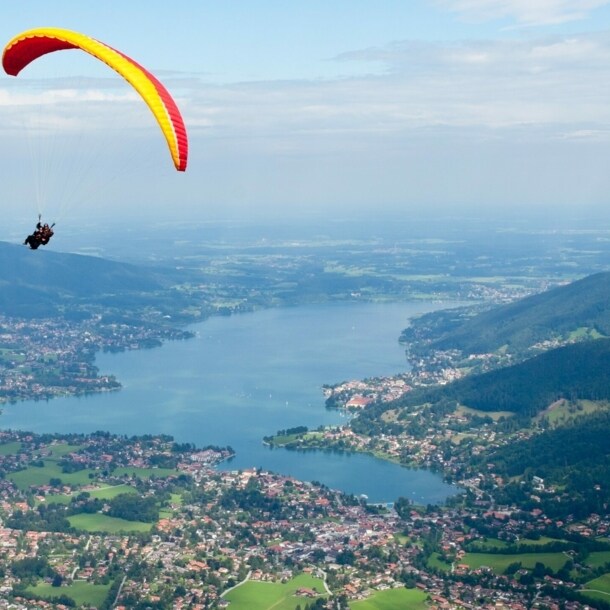 Gleitschirmflieger mit Blick von oben auf den Tegernsee