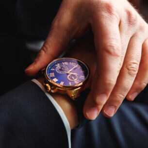 Eine Uhr an einem Handgelenk, die andere Hand fasst an das Armband der Uhr