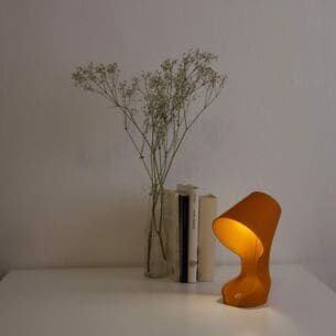 Eine orangefarbene Schreibtischlampe steht auf einem Tisch