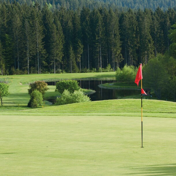 Eine rote Fahne auf dem hügeligen Golfplatz