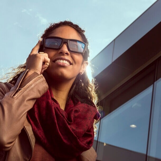 Eine Frau trägt eine Sonnenbrille die sie mit dem Fingern antippt