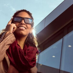 Eine Frau trägt eine Sonnenbrille die sie mit dem Fingern antippt