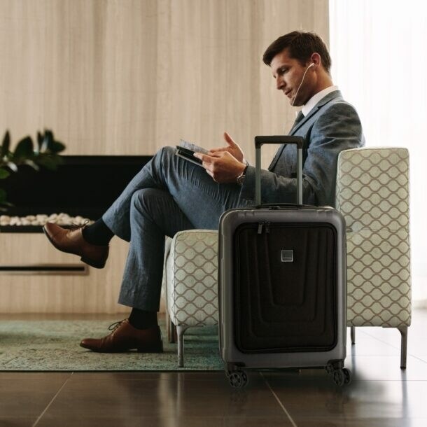 Ein Mann in einem Sessel, neben ihm steht ein Koffer