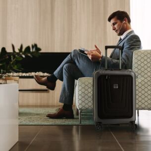 Ein Mann in einem Sessel, neben ihm steht ein Koffer