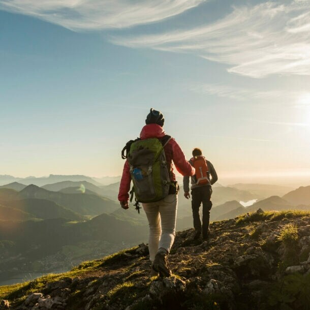 Zwei Personen wandern auf einem Berg mit beeindruckendem Panorama.