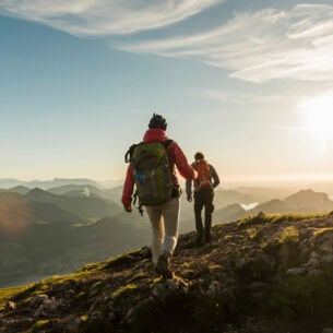 Zwei Personen wandern auf einem Berg mit beeindruckendem Panorama.