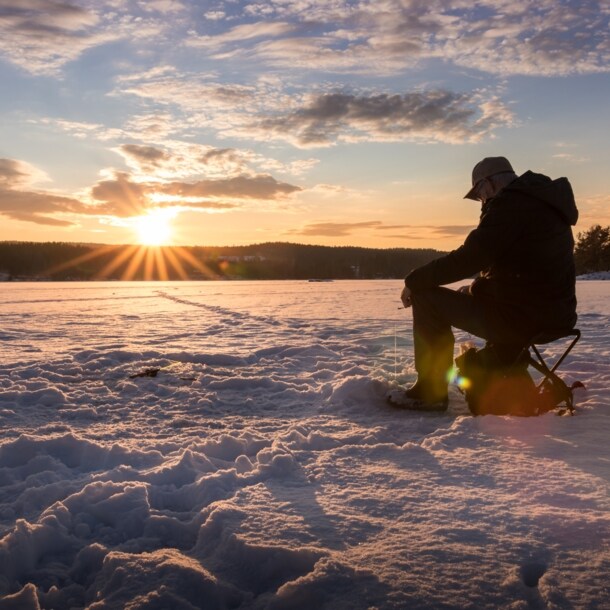Ein Eisangler sitzt auf einem zugefrorenen See