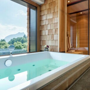 Bad eines Hotelzimmers mit Sauna, Jacuzzi und Panoramablick in die Natur